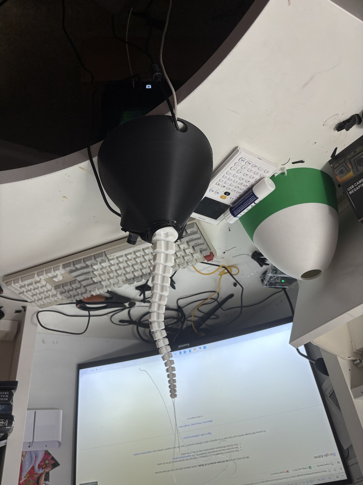 Segmented white soft robot arm mounted on its black actuation base
